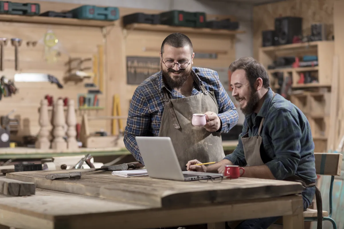 Two carpenters looking at a laptop in a workshop