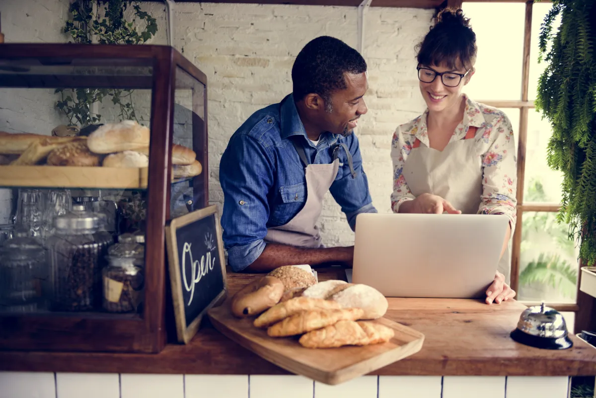Two business owners in a bakery looking at a laptop