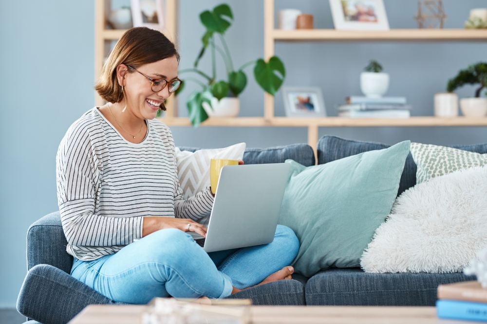 Woman sitting cross-legged on sofa using a laptop